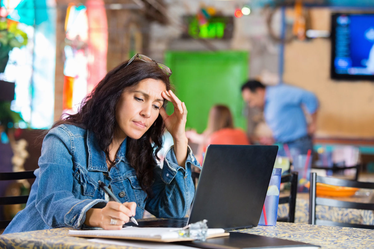 Worried-young-businesswoman-checking-finances-on-computer-in-restaurant-539269077_5600x3733